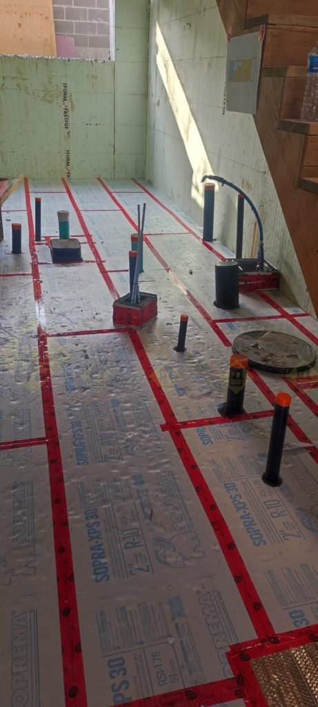 Basement concrete floor insulation installation in Toronto with rigid foam panels placed over gravel bedding before concrete pour.
