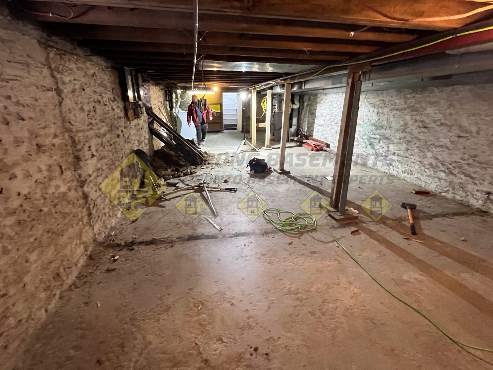 Unexcavated basement with an old concrete floor and a conveyor belt installed through a window, preparing for a basement lowering and underpinning project in Leaside, Toronto.