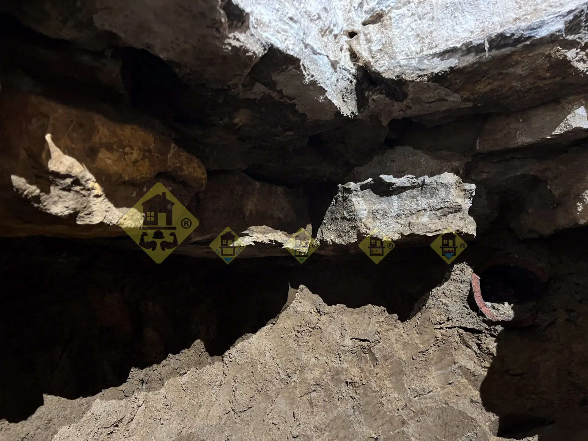 The uneven rock bottom of an exposed corner stone foundation wall during a basement lowering and underpinning excavation in Leaside, Toronto.