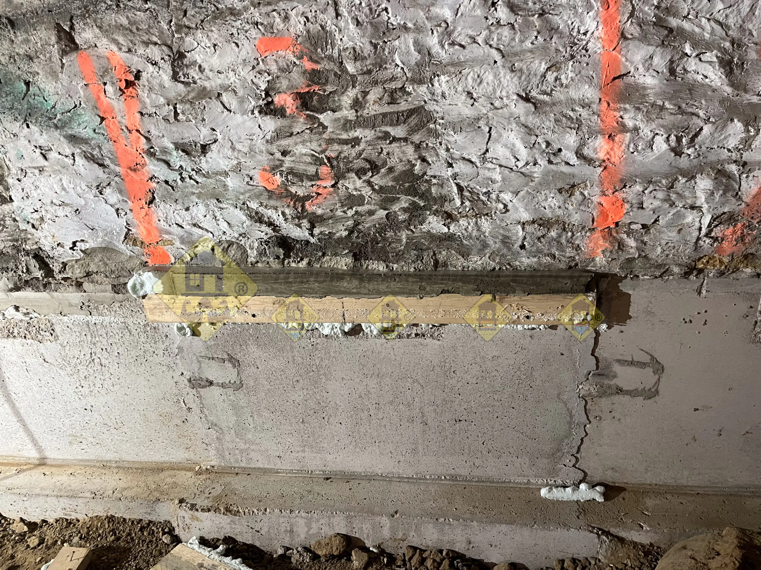 A solid 2-inch thick layer of cured non-shrink grout visible after removing wood forms, sealing the gap between the new concrete underpinning and old stone foundation in Leaside, Toronto.