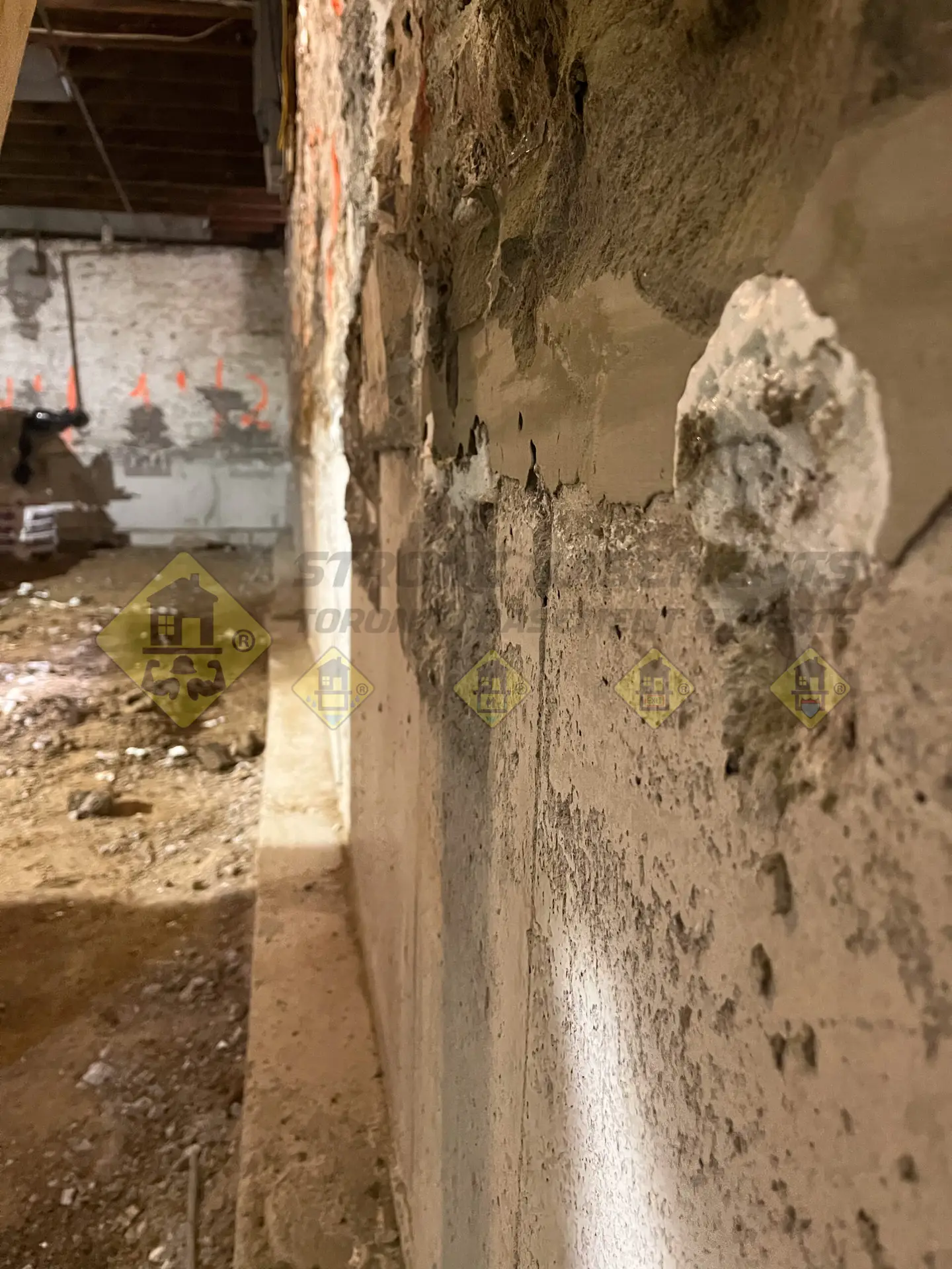 Side view of a fully underpinned foundation wall featuring flush concrete and an continuous L-shaped footing along the basement perimeter during a lowering project in Leaside, Toronto.