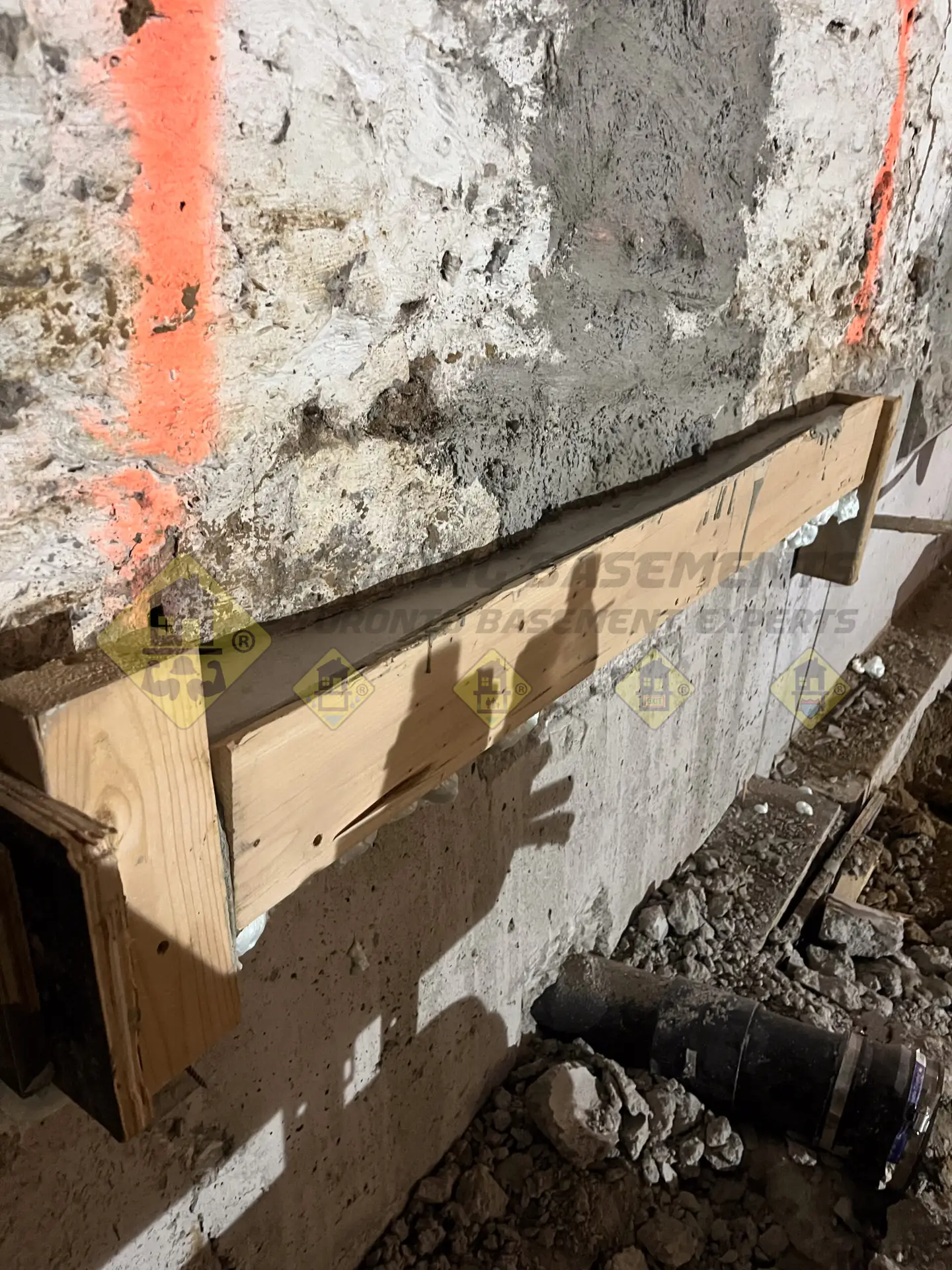 Liquid non-shrink grout poured into custom wood forms on top of a concrete underpinning section, filling the well higher than the original stone footing to completely seal the gap during a Leaside basement project.