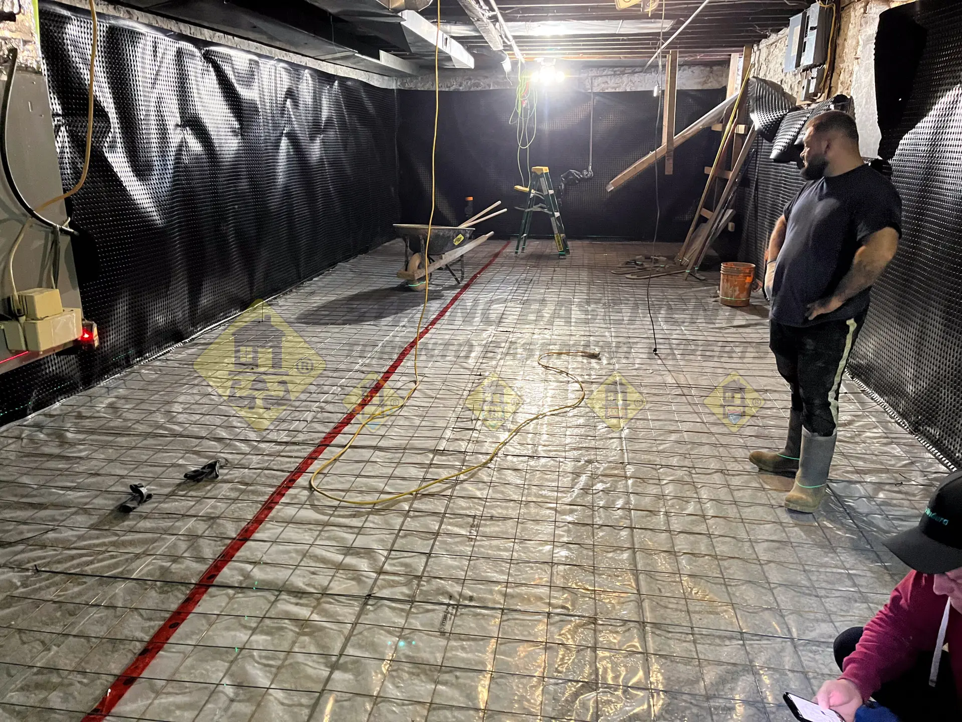 A 6-mil poly moisture barrier and steel welded wire mesh installed over compacted gravel bedding, preparing for a new concrete basement floor pour in Leaside, Toronto.