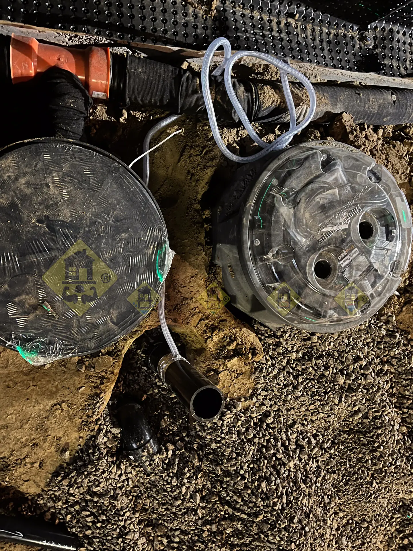 A newly installed sewage ejector pump sitting next to a sump pump system, with underground drainage pipe locations marked in spray paint during a basement lowering project in Leaside, Toronto.