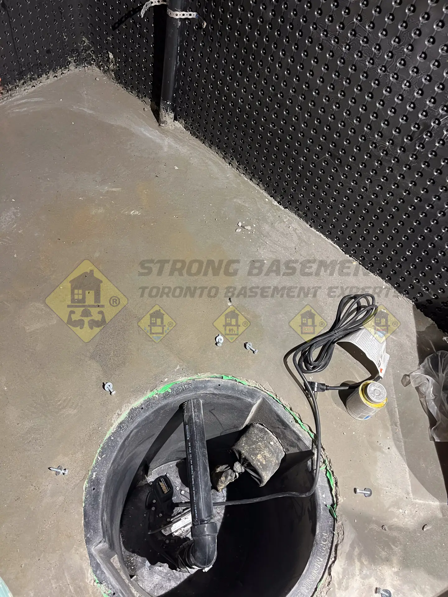 A newly installed sump pump sitting inside a secure sump tank, properly connected to a 1.5-inch ABS drainage outlet pipe in a lowered Leaside, Toronto basement.