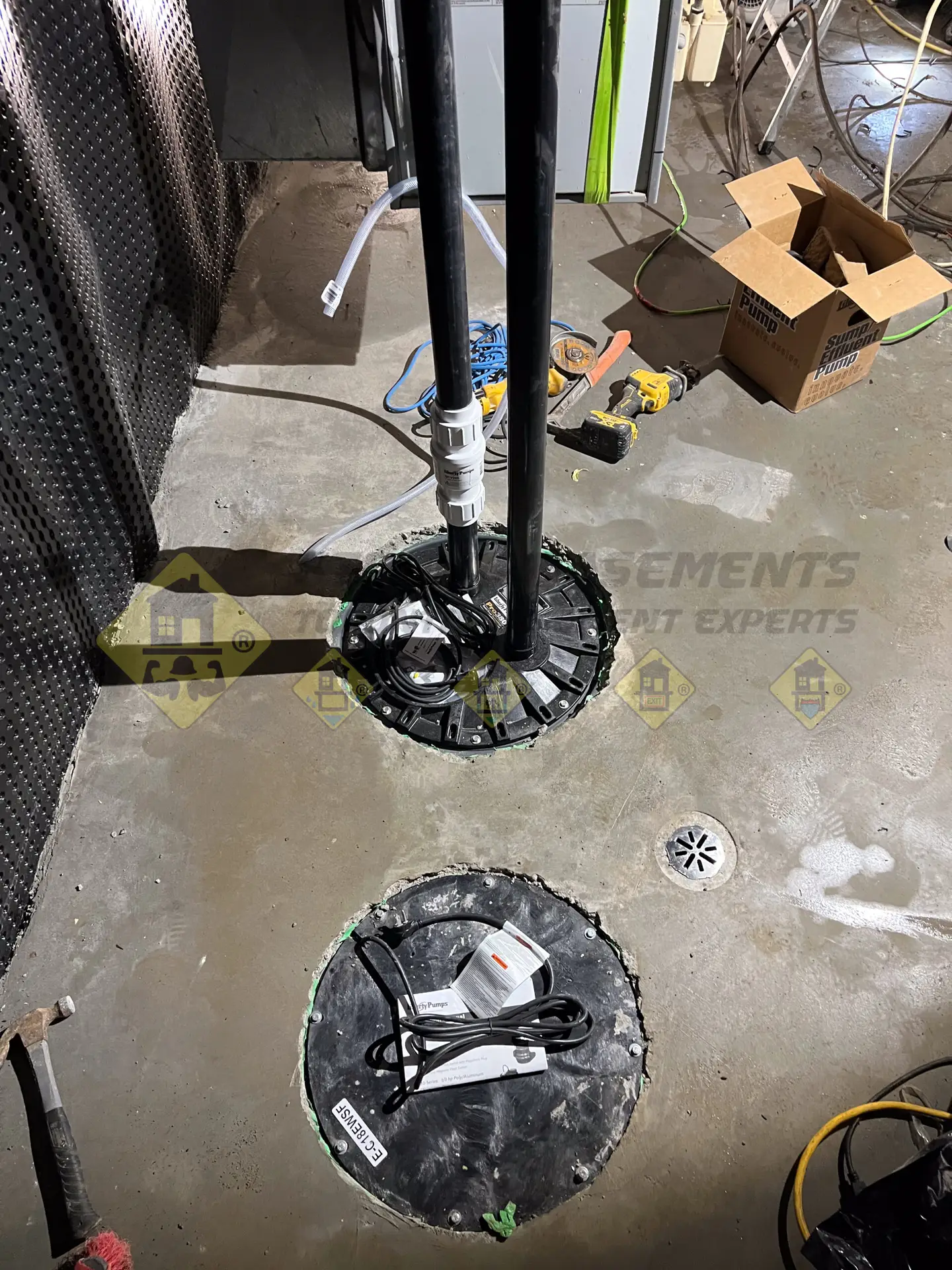 A fully installed sump pump, sewage ejector system, and concrete floor drain ready for usage in a newly lowered and waterproofed basement in Leaside, Toronto.