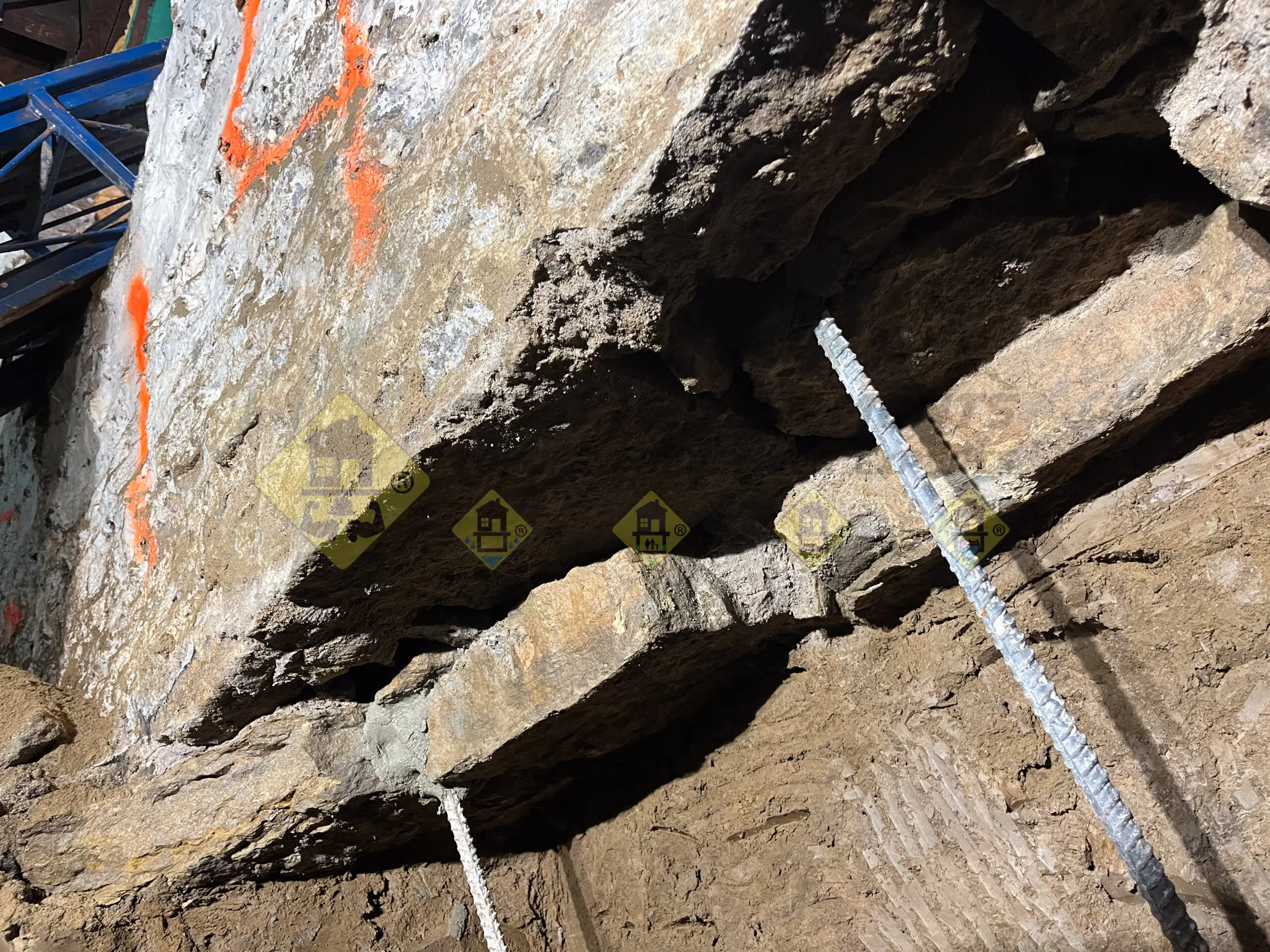 Close-up of an uneven natural stone foundation bottom with vertical steel rebars securely attached, preparing for concrete underpinning in a Leaside, Toronto basement.